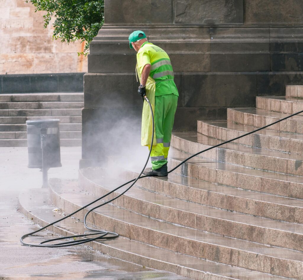 pexels photo 14965464 14965464 A street worker pressure washes stone stairs in a public park, ensuring cleanliness and safety.